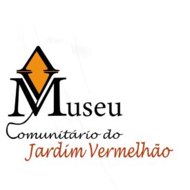 Logo do Museu Comunitário do Jardim Vermelhão. Acima da legenda, em 3 linhas, uma pipa de cor laranja e contorno preto, cuja parte de baixo forma a letra V de "VM", sendo que o M é a inicial da legenda Museu, na cor preta. Na linha de baixo, a rabiola da pipa inicia a letra "C" da legenda "Comunitário do", na cor preta; e na última linha a legenda "Jardim Vermelhão", na cor vermelha.