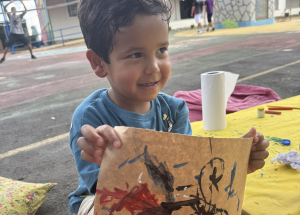 Criança, visitando o Museu e mostrando seu desenho realizado na oficina