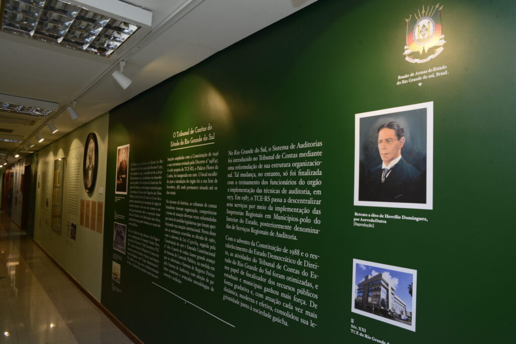 Uma parede com textos e imagens da parte final da exposição em fundo verde. mostrando a criação do TCE-RS.