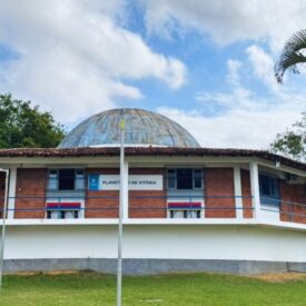 O projeto de criação do Planetário de Vitória teve sua origem nos primeiros anos da década iniciada em 1980, quando, pela primeira vez, a Associação Astronômica Galileu Galilei (AAGG), uma associação de astrônomos amadores, sediada em Vitória, ES, apresentou à Prefeitura Municipal de Vitória (PMV) uma proposta de aquisição, pela Prefeitura, de um projetor planetário e sua instalação no Município. Nessa época, contudo, não houve condições de o projeto ser implementado. Ao longo dessa mesma década, porém, aconteceu um evento astronômico marcante: a passagem do cometa Halley próximo ao Sol e a Terra, no final de 1985 e início de 1986. Graças a esse evento que, à época, teve enorme repercussão junto ao público e à mídia, a Universidade Federal do Espírito Santo (UFES) mobilizou esforços no sentido de atender ao grande interesse da comunidade pelo evento, construindo um observatório astronômico didático – o Observatório Astronômico da UFES (OA-UFES) – no Campus da UFES, em Goiabeiras, sob a responsabilidade do Departamento de Física, no qual foi instalado o telescópio Zeiss Meniscas-Cassegrain, com espelho de 15 cm, que já estava na UFES há alguns anos. O Observatório foi então inaugurado em fevereiro de 1986, bem a tempo de observar o cometa Halley durante essa sua última passagem (a próxima só ocorrerá em 2061!). Após a inauguração do OA-UFES, nesse mesmo ano de 1986, por meio do projeto de extensão “Observações Astronômicas”, a Universidade começou a prestar um serviço regular de atendimento à população em sessões semanais de visitação e observação do céu no Observatório, de cuja execução participavam professores do Departamento de Física da UFES, membros da Associação Astronômica Galileu Galilei e estudantes da UFES. Graças ao sucesso da parceria entre UFES e AAGG na execução do projeto Observações Astronômicas, o projeto de criação do Planetário de Vitória foi retomado por estas duas entidades, que buscaram o apoio de outras instituições públicas, como a própria PMV e o governo do estado do Espírito Santo. Desta feita, graças à parceria estabelecida e o esforço conjunto realizado pela UFES, o Governo do Estado do ES, via Secretaria de Estado da Educação (SEDU), a Prefeitura Municipal de Vitória (PMV) e a AAGG foi possível viabilizar o projeto de criação do Planetário, cabendo ressaltar o papel destacado desempenhado pela Associação Astronômica Galileu Galilei, responsável pelo projeto original de criação do Planetário e articuladora do apoio e envolvimento da UFES, Governo do Estado e PMV na sua viabilização. A UFES, via Ministério da Educação, adquiriu o projetor planetário, modelo Zeiss ZKP-2P, e a Prefeitura Municipal da Vitória construiu o prédio, com uma sala de projeção (cúpula) de 10 metros de diâmetro para instalação do projetor. O Planetário de Vitória foi, assim, inaugurado em 23 de junho de 1995 no Campus da UFES, em Goiabeiras, próximo ao Observatório Astronômico, iniciando suas atividades a partir desta data, dando continuidade às mesmas por meio de uma parceria entre a UFES e a PMV. No âmbito da UFES, desde sua criação, o Planetário acha-se vinculado ao Centro de Ciências Exatas e ao seu Departamento de Física, incumbido de indicar o seu Diretor Técnico-Científico dentre os professores do Departamento atuantes na área da Astronomia e Astrofísica. No âmbito da PMV, após um período inicial de indefinição, em que esteve vinculado à Secretaria Municipal de Esporte e Cultura e, depois, à de Administração e Finanças, em 1997, passou a subordinar-se à Secretaria Municipal da Educação (SEME), sendo, mais tarde, incorporado ao projeto “Escolas da Ciência” da SEME/PMV, passando a ser considerado como um de seus módulos, juntamente com a Praça da Ciência, a Escola da Ciência – Física e a Escola da Ciência – Biologia e História. A partir de 2002, após um reforço na sua equipe, com mais professores efetivos da SEME e maior número de planetaristas e estagiários, o Planetário de Vitória passou a diversificar bastante suas atividades, oferecendo, além das tradicionais sessões de planetário, também diversas outras, tais como oficinas, minicursos, palestras, cursos de formação continuada para professores, exposições e eventos científico-culturais diversos, tais como campanhas de observação de eclipses, o I Seminário de Educação em Ciências: o Papel dos Espaços de Educação Não-Formal na Educação em Ciências, promovido em conjunto com as demais Escolas da Ciência da SEME/PMV, em 2005, e sediando a XI Reunião da Associação Brasileira de Planetários, realizada em Vitória, em 2006. Atualmente, o Planetário vem atendendo a um público anual de cerca de 20 a 30 mil pessoas. Buscando promover o seu desenvolvimento e cumprir da melhor maneira possível sua missão de ensinar, divulgar e popularizar a Astronomia e ciências correlatas, o Planetário vem buscando estabelecer novas parcerias e elaborar projetos a serem encaminhados a órgãos de fomento, na área da Educação, Difusão e Popularização da Ciência e Tecnologia. Alguns dos principais resultados desse esforço foram: – Obtenção do patrocínio da Companhia Siderúrgica de Tubarão (CST), em 2004, para execução do projeto “Informatização do Planetário de Vitória”, por meio do qual foi possível aprimorar o uso das tecnologias da informação no ambiente e procedimentos de trabalho do Planetário, visando maior eficiência, flexibilidade e qualidade na criação e execução de suas atividades. – Apoio da UFES, especialmente do seu Departamento de Engenharia Elétrica, a partir de 2005, para o desenvolvimento de um novo projeto de automação do projetor planetário Zeiss ZKP-2P, em substituição ao projetor original, já ultrapassado e de difícil manutenção, que vem permitindo modernizar e aprimorar os recursos de automação do planetário e baratear sobremaneira o seu custo de manutenção. – Colaboração com o Centro de Formação Continuada em Ciências e Matemática da UFES (CeFoCo/UFES), entre 2004 e 2008, visando o desenvolvimento de materiais didáticos e cursos semi-presenciais e a distância para professores da Educação Básica e Infantil, na área de Ciências e Matemática. – Aprovação do projeto “Difusão, Ensino e Aprendizagem de Astronomia e Ciências em Espaços de Educação Não-Formal e por Meio do Uso de Tecnologias de Informação e Comunicação”, junto à Fundação de Amparo à Pesquisa do Espírito Santo (FAPES), em 2009. O projeto objetiva preparar e implementar ações educacionais na área da Astronomia e Ciências, por meio de espaços de educação não-formal, uso de Tecnologias de Informação e Comunicação (TIC) e da promoção e apoio à formação continuada e inicial de professores da Educação Básica e de mediadores para atuação em atividades de difusão científica. A estratégia básica utilizada no projeto é buscar promover uma articulação e sinergia entre as três vias acima citadas: espaços de educação não-formais, formação de professores e mediadores e uso das TICs. A implementação do presente website do Planetário de Vitória, que deverá permitir agendamento on-line para visitas de turmas de escolas ao Planetário, fomentar atividades escolares integradas à visita ao Planetário, e a consulta a conteúdos de Astronomia e de Educação em Astronomia especialmente voltados ao professor da Educação Básica, faz parte dessa estratégia importante. Dessa forma, o Planetário vem se caracterizando por ser uma instituição que funciona como um laboratório de ensino e difusão científica que busca integrar-se à sociedade, estabelecer parcerias e angariar apoio visando cumprir sua missão educacional da maneira mais ampla possível, buscando levar a cultura técnico-científica a uma parcela cada vez mais ampla da população, contribuindo, assim, para o desenvolvimento sócio-cultural e exercício da cidadania em nosso estado e país.