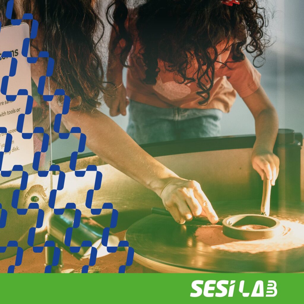 Criança e mulher criando padrões com areia vermelha no aparato Padrões Giratórios.